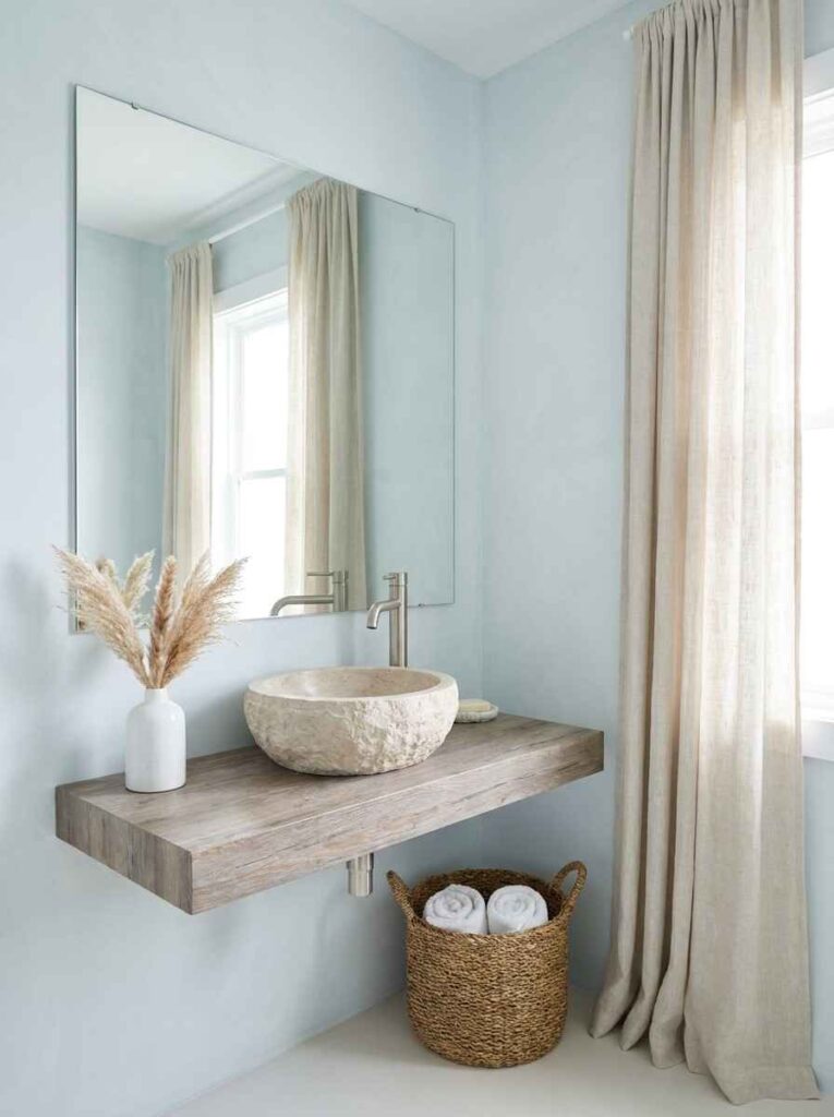 20 Bathroom Ideas 2026 A serene coastal bathroom with soft pale blue walls in a barely-there tone reminiscent of Benjamin Moore Breath of Fresh Air.